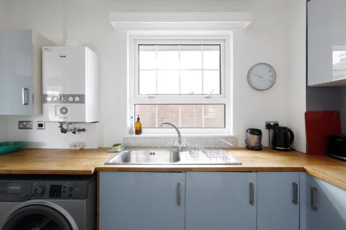 罗廷丁Charming 1 bedroom apartment in Rottingdean的白色的厨房设有水槽和窗户