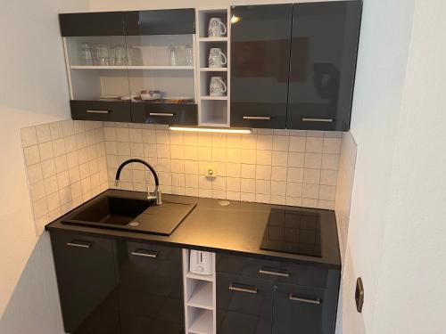 哈廷根Ferienwohnung Blankenstein的厨房配有黑色橱柜和水槽