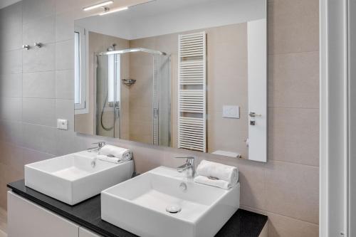巴多利诺Oleandro Holiday Apartments的浴室设有2个白色水槽和镜子