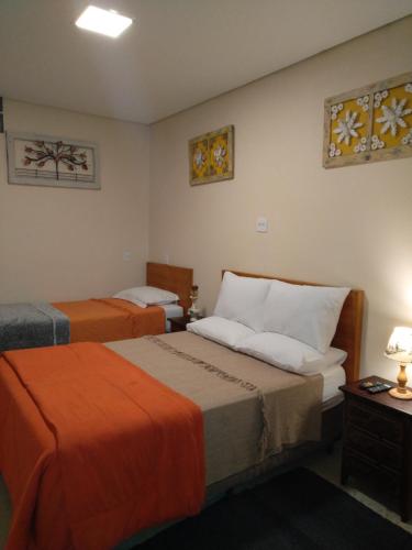 蒂拉登特斯Casa Temporada Tiradentes的酒店客房带两张带橙色床单的床