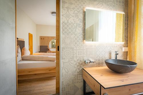 GaalLorettohof Hotel Garni的一间带碗水槽的浴室和一间卧室