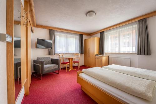 达米尔斯Hotel Garni Krumbach的配有床、椅子和桌子的酒店客房