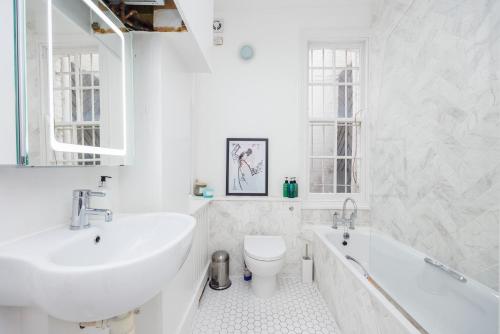 伦敦Dynamic in Dean Street的白色的浴室设有水槽、浴缸和卫生间。
