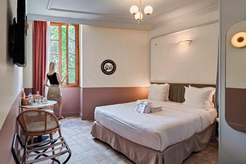 尼斯Aparthotel AMMI Vieux Nice的一位妇女站在酒店带床的房间