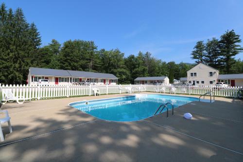 巴特利特The Villager Motel的一个带白色围栏和房屋的游泳池