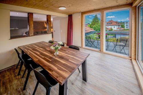 因特拉肯Swiss Inn & Apartments的一间带木桌和一些窗户的用餐室