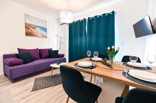 比比涅Apartments MENA的客厅配有桌子和紫色沙发