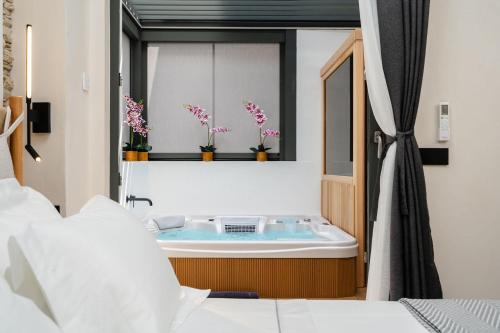 纳克索乔拉Legato Spa Suites的浴室设有窗户,配有鲜花浴缸