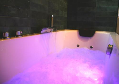 阿拉斯L'Eden Chic - Balneo - Jardin - Parking gratuit的粉红色的浴缸里装满了许多粉红色的水