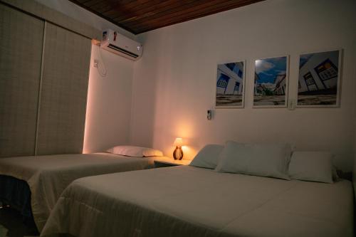 萨尔瓦多Duplex na beira da praia, de frente pro mar的一间卧室设有两张床和一张桌子上的台灯。