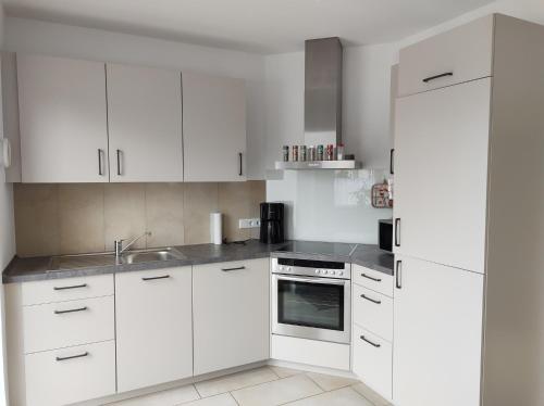 萨尔贝克FeWo Holunderbusch的白色的厨房配有白色橱柜和水槽