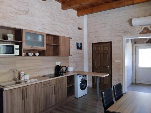 尼赖吉哈佐Pipacs Apartman的厨房配有木制橱柜、桌子和微波炉