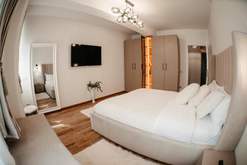 苏恰瓦Cosy apartment Bucovina的白色卧室设有一张大床和镜子