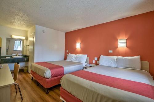 塔拉哈西Loyalty Inn Tallahassee的酒店客房,设有两张带红色墙壁的床