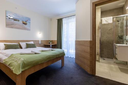 索波特KIWI Sopot Apartments的一间卧室设有一张床和一个玻璃淋浴间