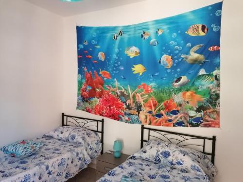 巴里萨尔多La Stella Marina的两张床位于带壁挂水族馆壁画的客房内。