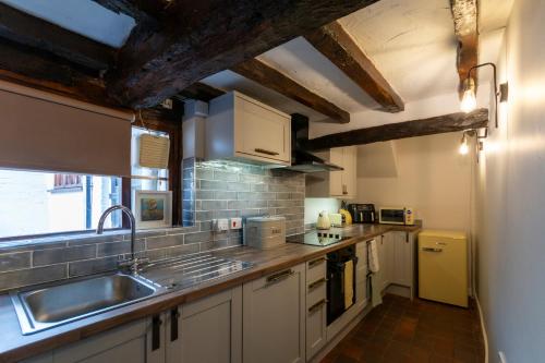 布由德利Bewdley River Cottage - Free private gated parking for 2 cars - River front location的厨房配有白色橱柜和水槽