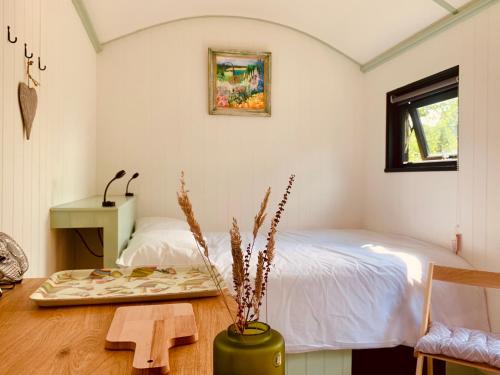 Staple CrossApple Orchard Shepherd Huts的一间卧室配有一张床、一张桌子和一张长凳