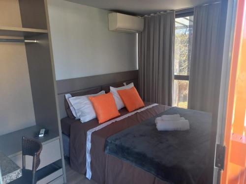 戈亚斯州上帕莱索Villa de Assis Suítes的一间卧室配有带橙色枕头的床和窗户。