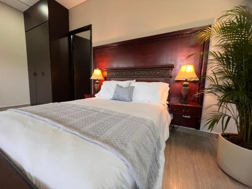 瓜塔佩1714 Hotel Boutique Guatapé的卧室配有白色大床和植物