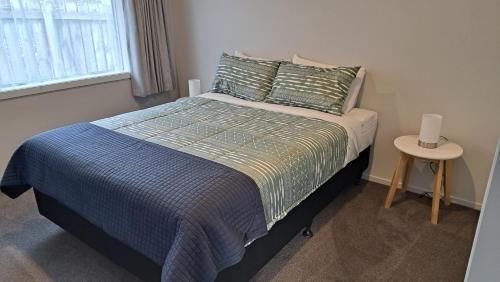 因弗卡吉尔South City Accommodation unit 4的一间卧室配有一张带蓝色棉被的床和一张桌子