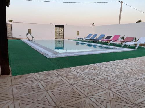 米多恩Belle Villa Avec Piscine sans vis a vis的一个带椅子的游泳池,并铺有绿色地板