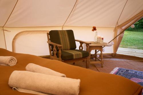DalbyHesselgaard Glamping的帐篷内的房间,配有椅子和桌子