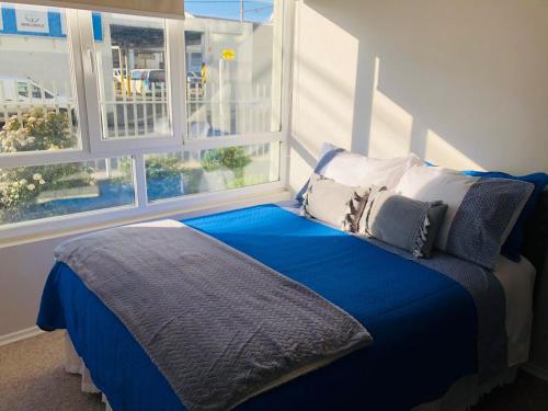 特木科Acogedor departamento en Temuco的一张带蓝色床单和枕头的床,靠窗
