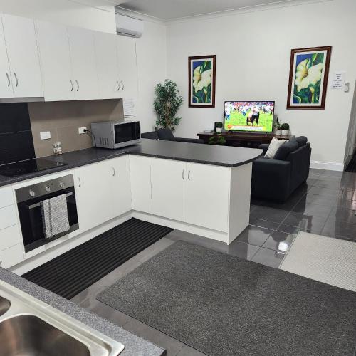 布罗肯希尔City Villa 39 Blende st Broken Hill NSW 2880的一间带白色橱柜的厨房和一间客厅