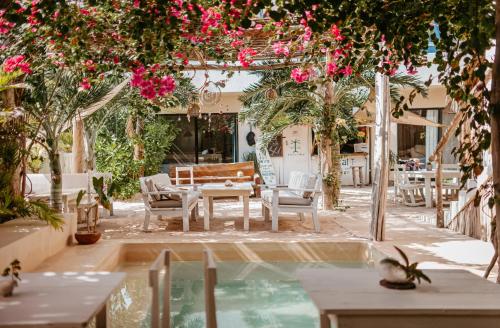 埃尔库约LunArena Boutique Beach Hotel Yucatan Mexico的庭院配有桌椅和粉红色的鲜花。
