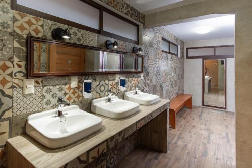 圣克里斯托瓦尔-德拉斯卡萨斯Tierra Alta Hostal的浴室设有两个盥洗盆和带两个镜子的台面