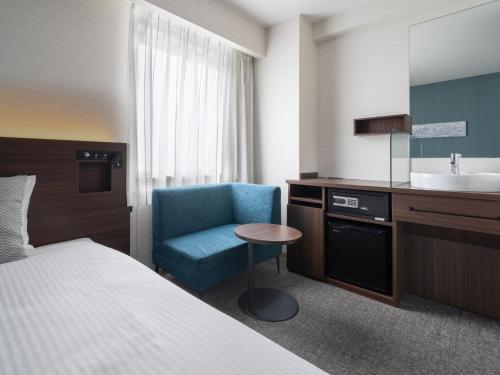 松山Hotel Vista Matsuyama的酒店客房设有床、水槽和椅子
