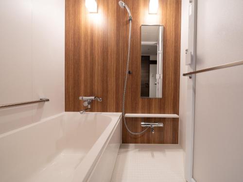 松山Hotel Vista Matsuyama的浴室配有浴缸、淋浴和镜子