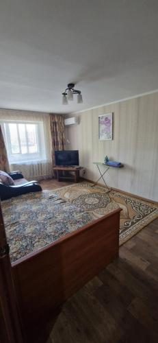 卡拉甘达Однокомнатная квартира в Караганде的客厅的地板上铺有大地毯