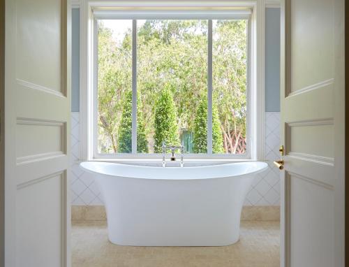 罗兰低地Le Mas Barossa的带浴缸的浴室和窗户