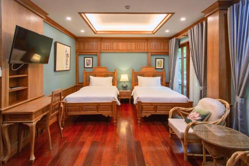 清迈富园之家酒店的客房设有两张床、一张桌子和一台电视机。