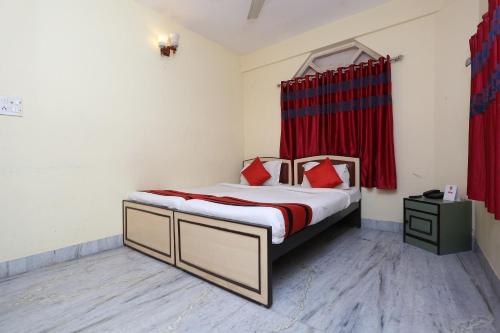 Ālīpur阿里波利旅馆的一间卧室配有红色窗帘的床