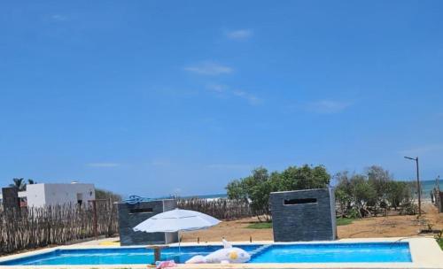 Celestino GascaTres Velas Surf的一个带遮阳伞和白色填充物的游泳池