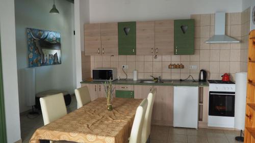 Tomajmonostora托玛杰公寓的一个带桌椅的厨房和一个带绿色橱柜的厨房