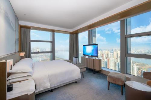 武汉武汉江夏联投福朋喜来登酒店的一间卧室设有一张床、一台电视和大窗户