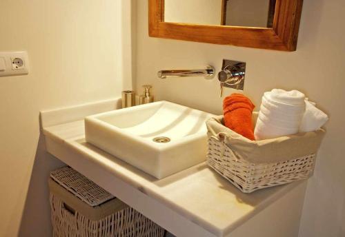 赫罗纳Mas Garriga Turisme Rural的浴室水槽,配有毛巾篮和镜子