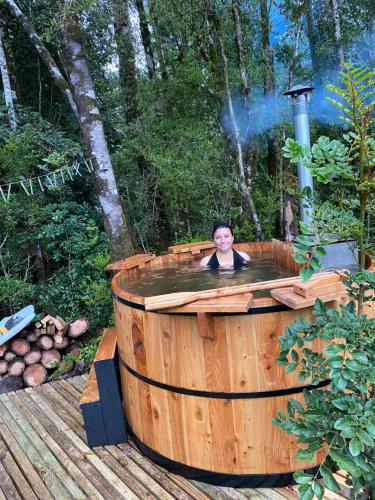 巴拉斯港Habitación en Casa Cumbres del Lago的一个人在木头上的热水浴缸中