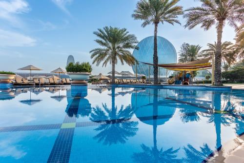 阿布扎比爱尔拉哈海滩酒店的一座棕榈树游泳池和一座建筑