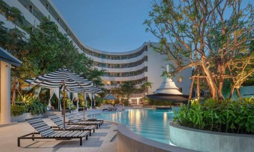 芭东海滩The Royal Paradise Hotel & Spa - SHA Extra Plus的一个带椅子和遮阳伞的游泳池和一座建筑