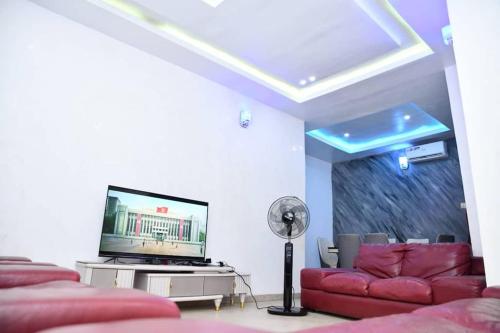 贝宁城Domi Smart 2 Bedroom Serviced Apartment with 24 hour Power的客厅配有红色沙发和平面电视