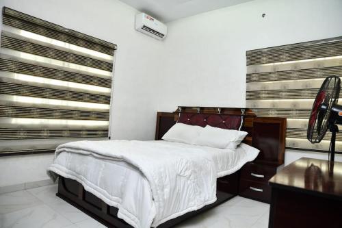 贝宁城Domi Smart 2 Bedroom Serviced Apartment with 24 hour Power的一间卧室设有一张大床和两个窗户。