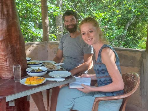 MonaragalaKande Gedara Resort (කන්දෙ ගෙදර)的坐在餐桌旁吃饭的男人和女人