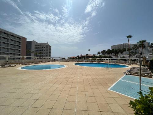 法纳贝海滩Lookout Point Tenerife Holiday Apartment Las Americas的两座游泳池位于带建筑的庭院内