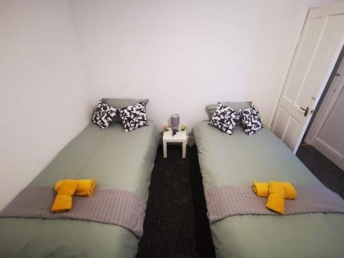 德比Twin Room - Sutherland Place的配有黄色和灰色枕头的客房内的两张床