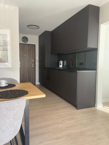 米泽德沃兹Apartamenty na Wydmach MK的厨房配有黑色橱柜和木桌